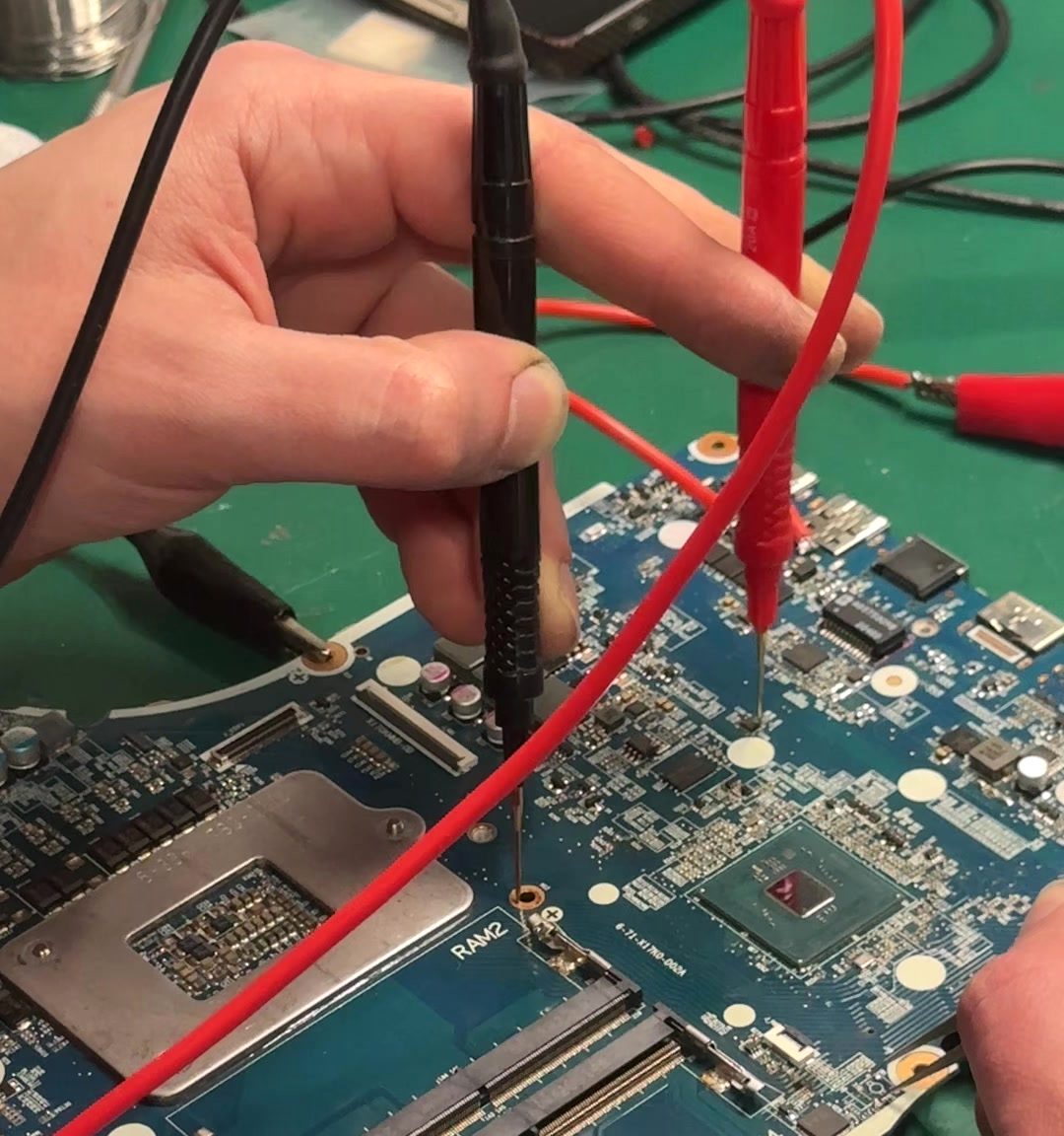 Measuring a laptop board's power rails to find the fault.